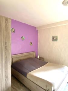 a bedroom with purple walls and a bed at Auberge de Cadenas in Veyreau