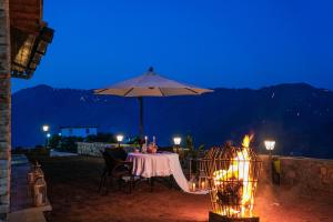 a table with an umbrella and a grill with lights at SaffronStays Ridgeview Manor, Mukteshwar - 3BHK Villa with Himalayan Views & Verandahs in Mukteshwar +50 photos