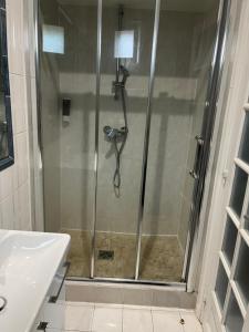 una ducha con puerta de cristal en un baño en Charmant studio, en Les Lilas