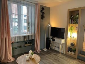 una sala de estar con un televisor y una mesa en Charmant studio, en Les Lilas