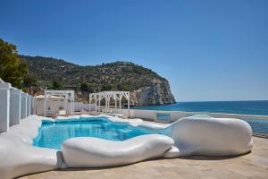 a swimming pool with white chairs next to the ocean at La Casa E Il Mare, Private Bay Hotel in Mattinata
