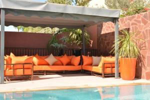 an outdoor seating area with orange pillows next to a pool at Atlas Royale Marrakech in Marrakesh