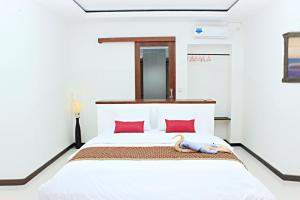 a bedroom with a white bed with red pillows at Alam Mimpi Hotel in Lajor