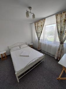 a bedroom with a white bed and a window at Casa Jolie in Constanţa