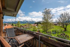 a wooden balcony with a wooden table and a bench at SCHMID Ferienwohnungen in Ofterschwang