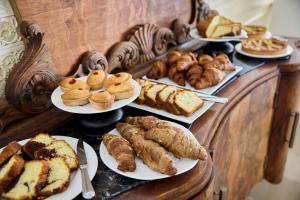 a table with different types of bread and pastries on plates at La Casa E Il Mare, Private Bay Hotel in Mattinata