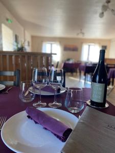 a table with a bottle of wine and wine glasses at Auberge de Cadenas in Veyreau +35 photos