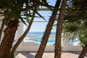 a view of the ocean through the palm trees at La Casa E Il Mare, Private Bay Hotel in Mattinata