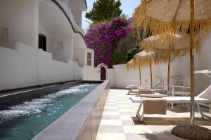 a pool with chairs and umbrellas next to a building at La Casa E Il Mare, Private Bay Hotel in Mattinata