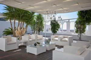 a patio with white chairs and tables and palm trees at La Casa E Il Mare, Private Bay Hotel in Mattinata