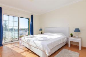 a white bedroom with a bed and a large window at Seasun Step Apartment in Praia da Rocha in Portimão +48 photos