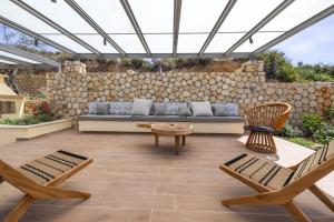 a patio with a couch and chairs and a stone wall at Zeus luxury Villas - Villa Ermis in Kefallonia