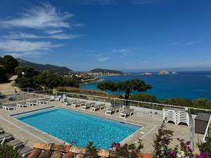 a swimming pool with chairs and a view of the ocean at Résidence Marine de Palumbare in LʼÎle-Rousse