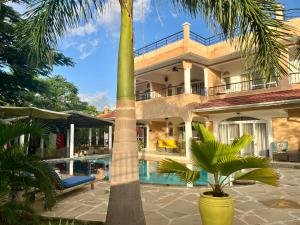 a house with a palm tree in front of a swimming pool at Barracuda House in Diani Beach