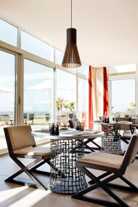 a dining room with tables and chairs and windows at Hotel Le Golf D'Essaouira & Spa in Essaouira