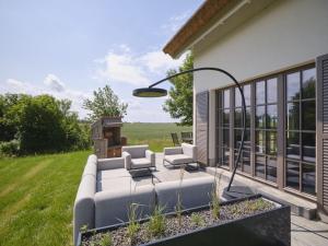 a patio with a couch and chairs on the side of a house at Reetland am Meer - LuxusPlus Reetdachvilla mit 4 Schlafzimmern, Außensauna, Loungebereich und Kamin H05 in Dranske
