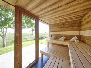 a sauna with a bench and a large window at Reetland am Meer - LuxusPlus Reetdachvilla mit 4 Schlafzimmern, Außensauna, Loungebereich und Kamin H05 in Dranske +17 photos
