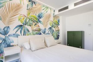 a bedroom with a white bed with a tropical wallpaper at Home2Book Design & Spacious Apartment City Center in Santa Cruz de Tenerife +25 photos