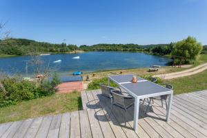 a table and chairs on a deck with a view of a lake at Haus PEAK am See in Zirkow