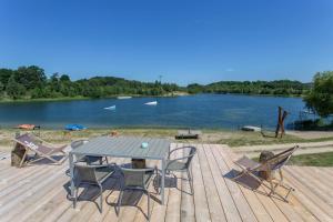 una terrazza in legno con tavolo, sedie e un lago. di Haus TAO, am See a Zirkow