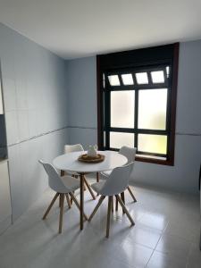 a table and chairs in a room with a window at Apartamento Ensenada de Barraña in Boiro +7 photos