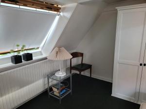 a room with a lamp and a chair and a window at Skrædderens Baghus in Assens