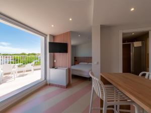 a hotel room with a balcony with a bed and a table at Apartamentos Sunway Atlanta in Sitges