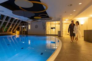 a man and woman standing next to a swimming pool at Kaiserhof Victoria in Bad Kissingen