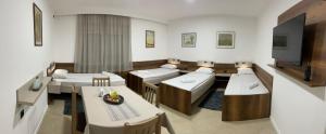 a room with three beds and a tv and a table at Kollar D Guest House - Prenoćište ROOMS in Subotica
