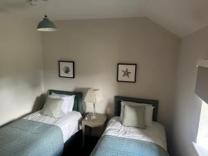 a bedroom with two beds and a table with a lamp at Darcy Magee Apartment No2 in Carlingford