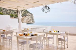 a restaurant with white tables and chairs and the ocean at La Casa E Il Mare, Private Bay Hotel in Mattinata