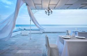a room with white tables and a view of the ocean at La Casa E Il Mare, Private Bay Hotel in Mattinata
