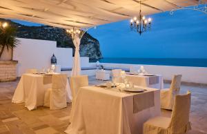 a room with tables and chairs with a view of the ocean at La Casa E Il Mare, Private Bay Hotel in Mattinata