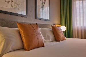 a bed with brown and white pillows in a room at Hotel Malcom and Barret in Valencia