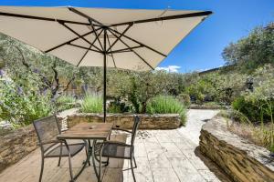 a table and chairs with an umbrella on a patio at Le Clos Saint Michel Resort & Spa in Malaucène