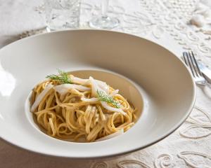 a white bowl of pasta on a table at La Casa E Il Mare, Private Bay Hotel in Mattinata