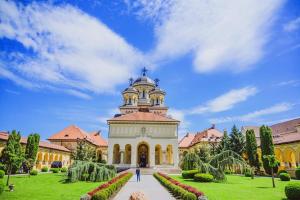 a building with a clock tower in a park at Zen Apartament in Alba Iulia