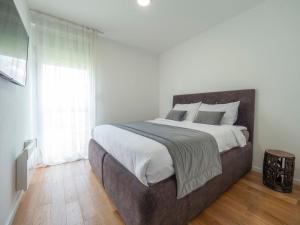 Un dormitorio con una cama grande con sábanas y almohadas blancas. en Classy Two-Bedroom Apartment, en Budva