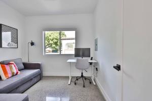 a living room with a couch and a desk with a computer at Bungalow near zoo and beach with AC, EV, private yard in San Diego