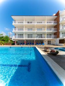 a swimming pool in front of a building at Apartamentos Sunway Amapola in Sitges