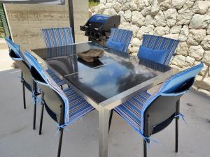 a glass table with four chairs and a grill at Villa Lucija in Ploče