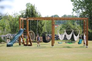 a boy is standing in a playground with swings at Avar puhkekompleks saunaga in Kuusiku