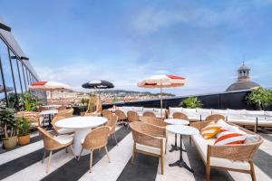 a rooftop patio with tables and chairs and umbrellas at Doubletree By Hilton Nice Centre Iconic in Nice