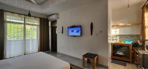 a bedroom with a bed and a tv on a wall at Villa Salaam in Diani Beach
