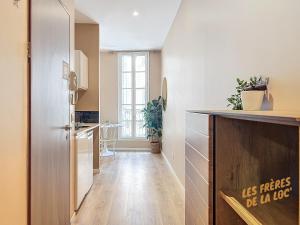 een keuken met witte muren en een houten vloer bij Magnifique Studio - Hyper Central & Climatisation - Les Frères de la Loc' in Marseille