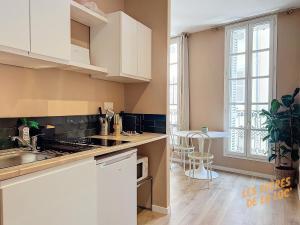 een keuken met witte kasten, een wastafel en een tafel bij Magnifique Studio - Hyper Central & Climatisation - Les Frères de la Loc' in Marseille