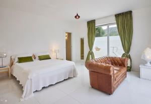 a white bedroom with a bed and a chair at La Casa E Il Mare, Private Bay Hotel in Mattinata
