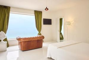 a bedroom with a leather chair in front of a window at La Casa E Il Mare, Private Bay Hotel in Mattinata