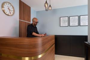a man standing at a reception desk with a cell phone at Timhotel Paris du Gare du Nord in Paris