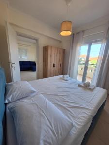 a large white bed in a bedroom with a window at Dimar3 Seaside Apartment in Paralia Dionysiou